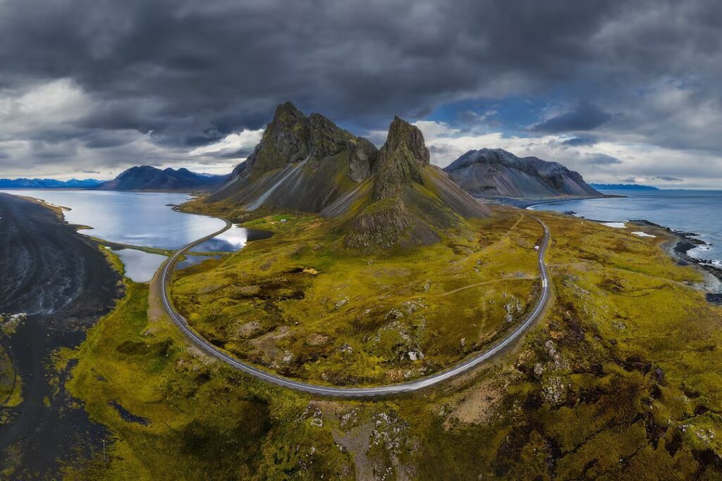 Aerial view of Iceland Ring Road winding through dramatic volcanic landscape with glaciers and green moss-covered lava fields