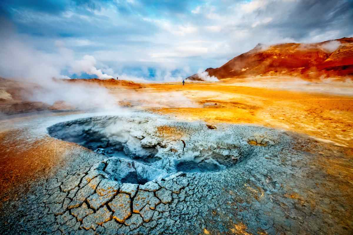 Myvatn geothermal area in northern Iceland with turquoise hot spring water steaming amid dark lava formations under a wide Arctic sky, natural spa honeymoon experience, editorial photography