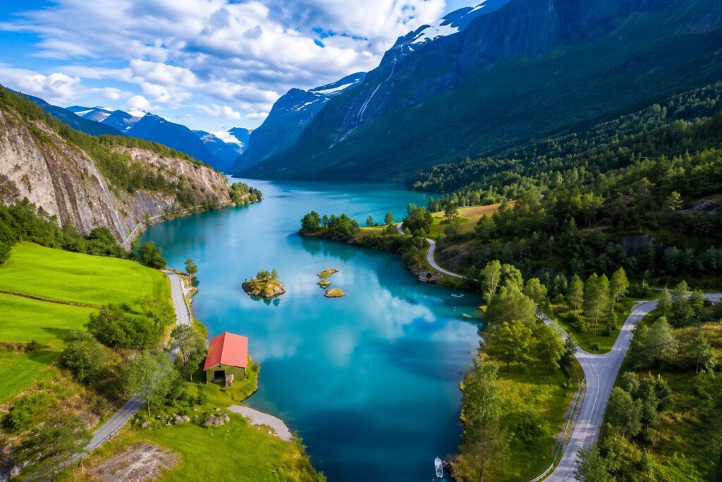 Panoramic aerial view of Geirangerfjord in Norway with deep blue water winding between steep green mountains and cascading wa