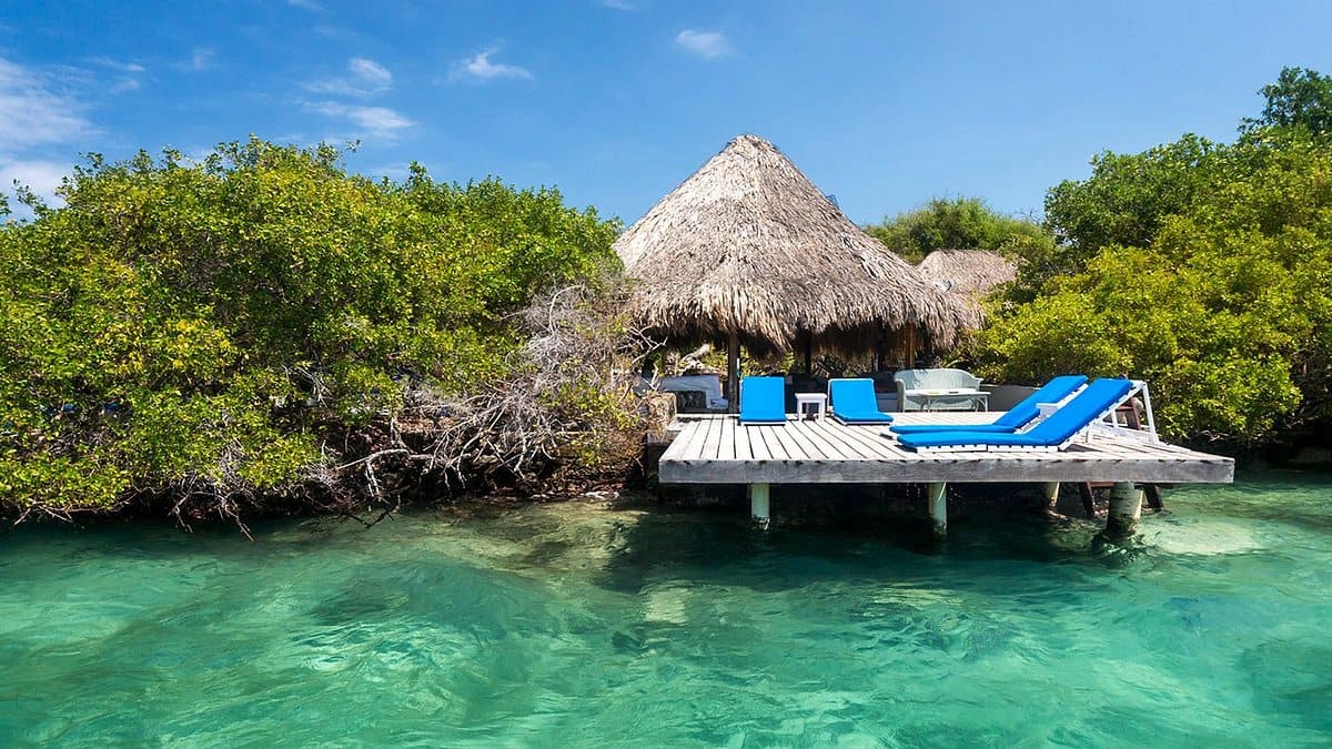Stilted overwater bungalow on a coral island off Sabah coast at sunset with calm turquoise water and palm trees, tropical island honeymoon finale, editorial photography