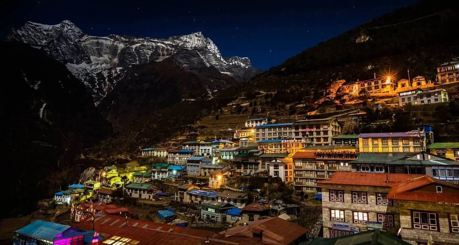 Heritage hotel terrace in Nepal overlooking terraced green hillsides and distant Himalayan peaks at golden hour with traditional carved wooden railing, luxury Nepal honeymoon planning, editorial photography
