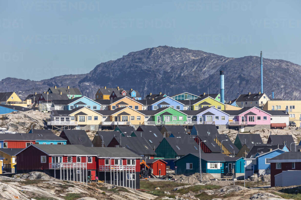 Panoramic view of Ilulissat Icefjord Greenland with massive icebergs in deep blue water and colourful town houses on the hill