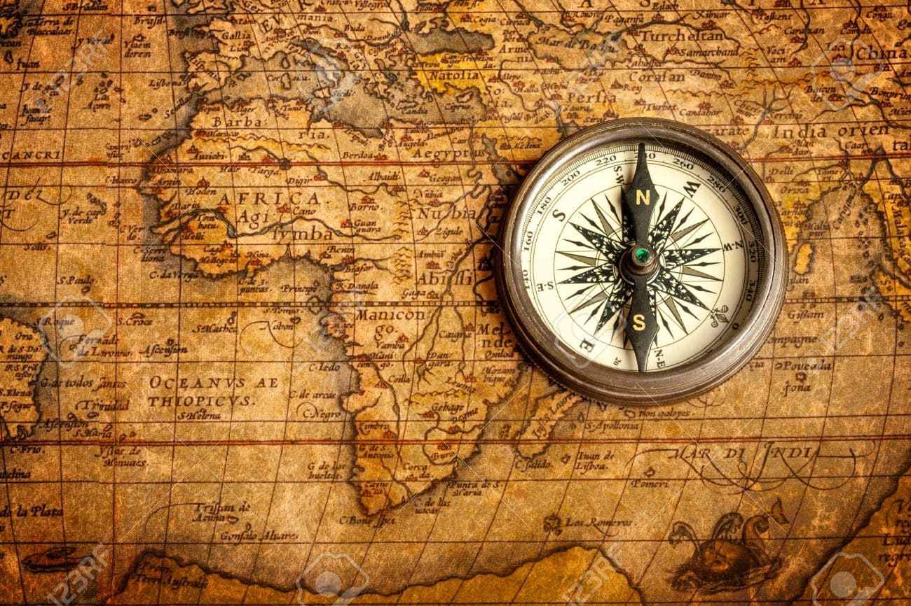 Compass and vintage map on a wooden table with warm light suggesting travel planning and decision-making for an unconventional honeymoon, editorial lifestyle photography