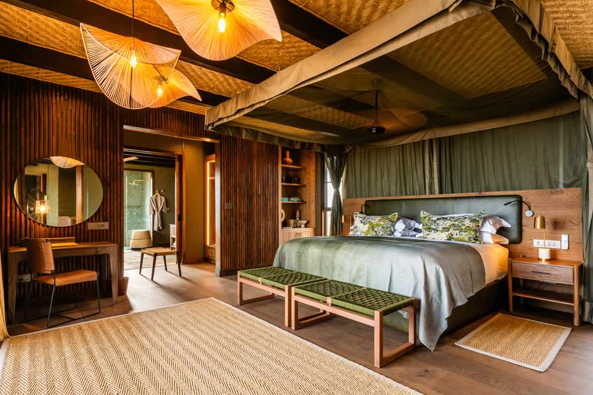 Intimate lodge interior with warm lighting and large window overlooking a dramatic natural landscape at dusk, off-the-beaten-path honeymoon accommodation planning, editorial photography