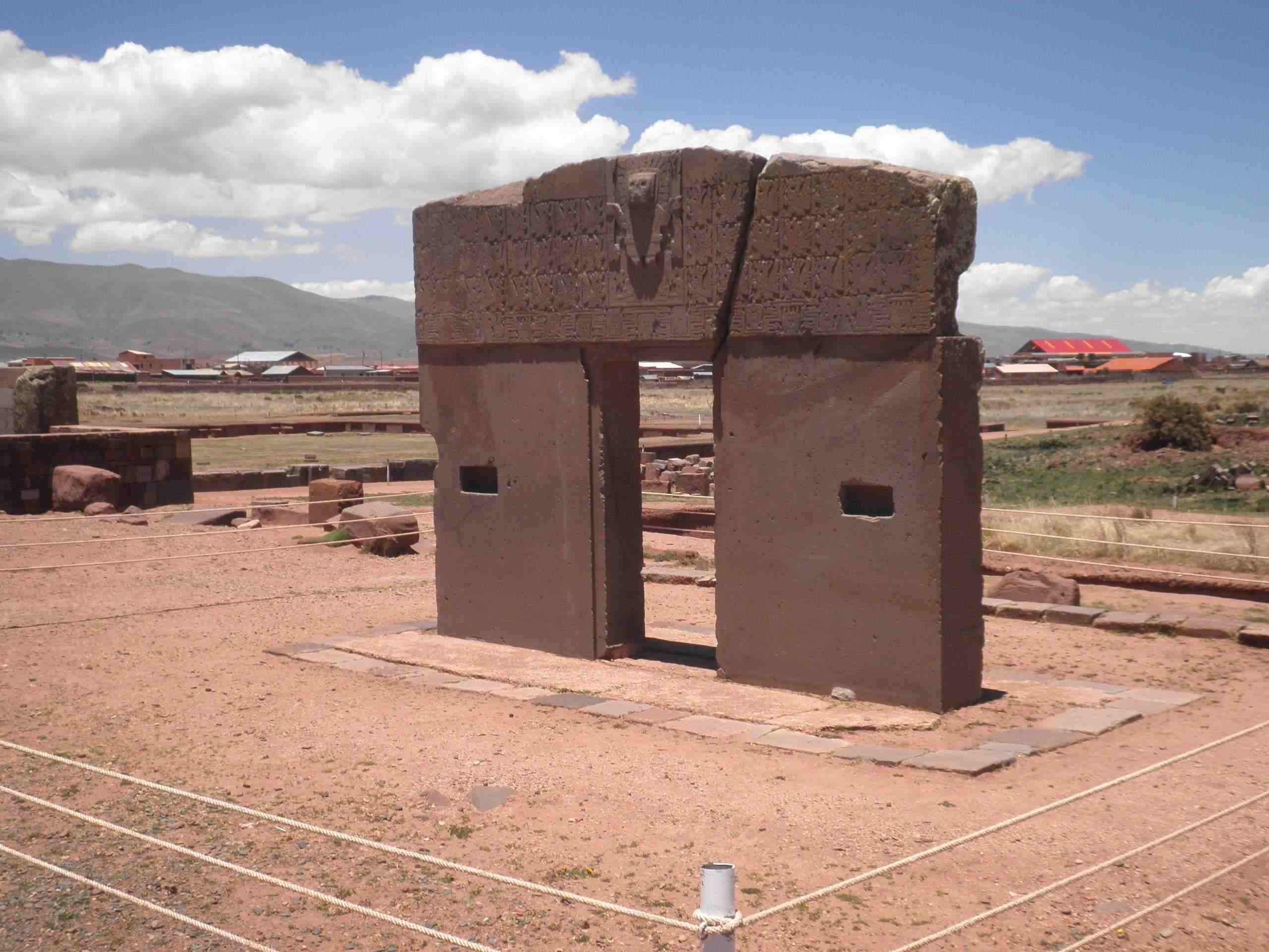 Ancient stone Gateway of the Sun at Tiwanaku archaeological site Bolivia with intricate carved figures and vast Altiplano landscape behind, pre-Inca cultural honeymoon heritage, editorial photography