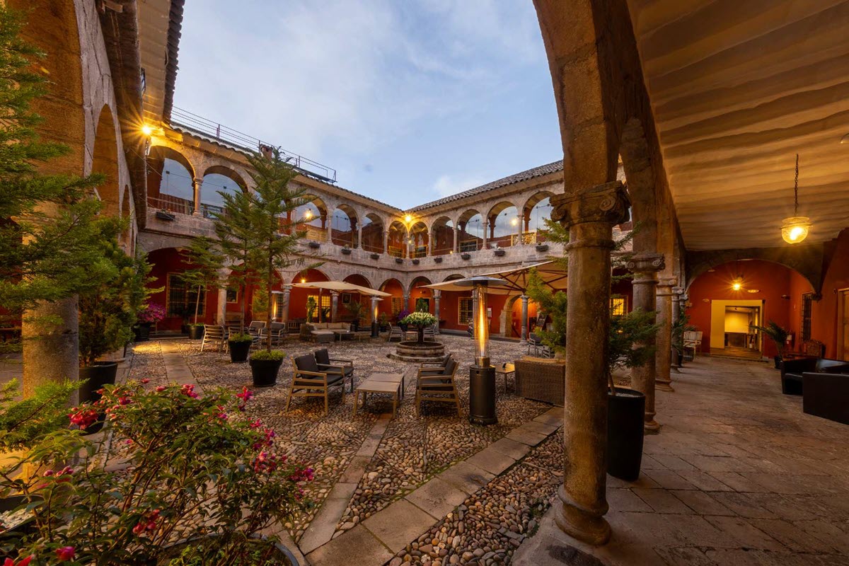 Heritage hotel courtyard with traditional carved architecture and warm evening light casting shadows on stone floors, luxury cultural honeymoon planning, editorial photography