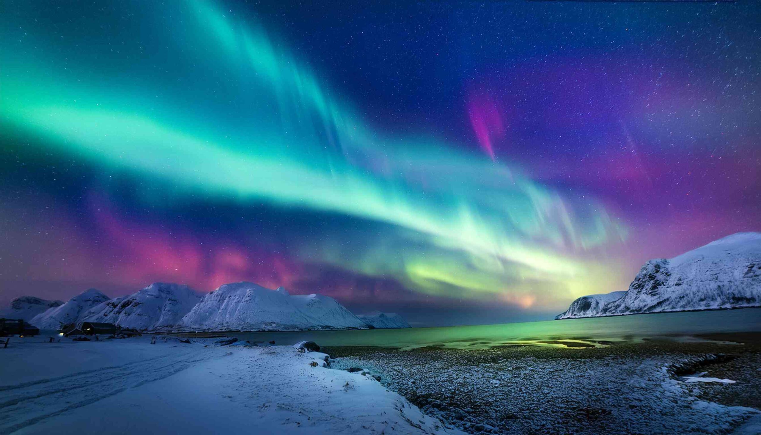 Vivid green and purple aurora borealis dancing across a dark Arctic sky above a snow-covered landscape with a warm cabin glow in the distance, northern lights honeymoon atmosphere, editorial photography
