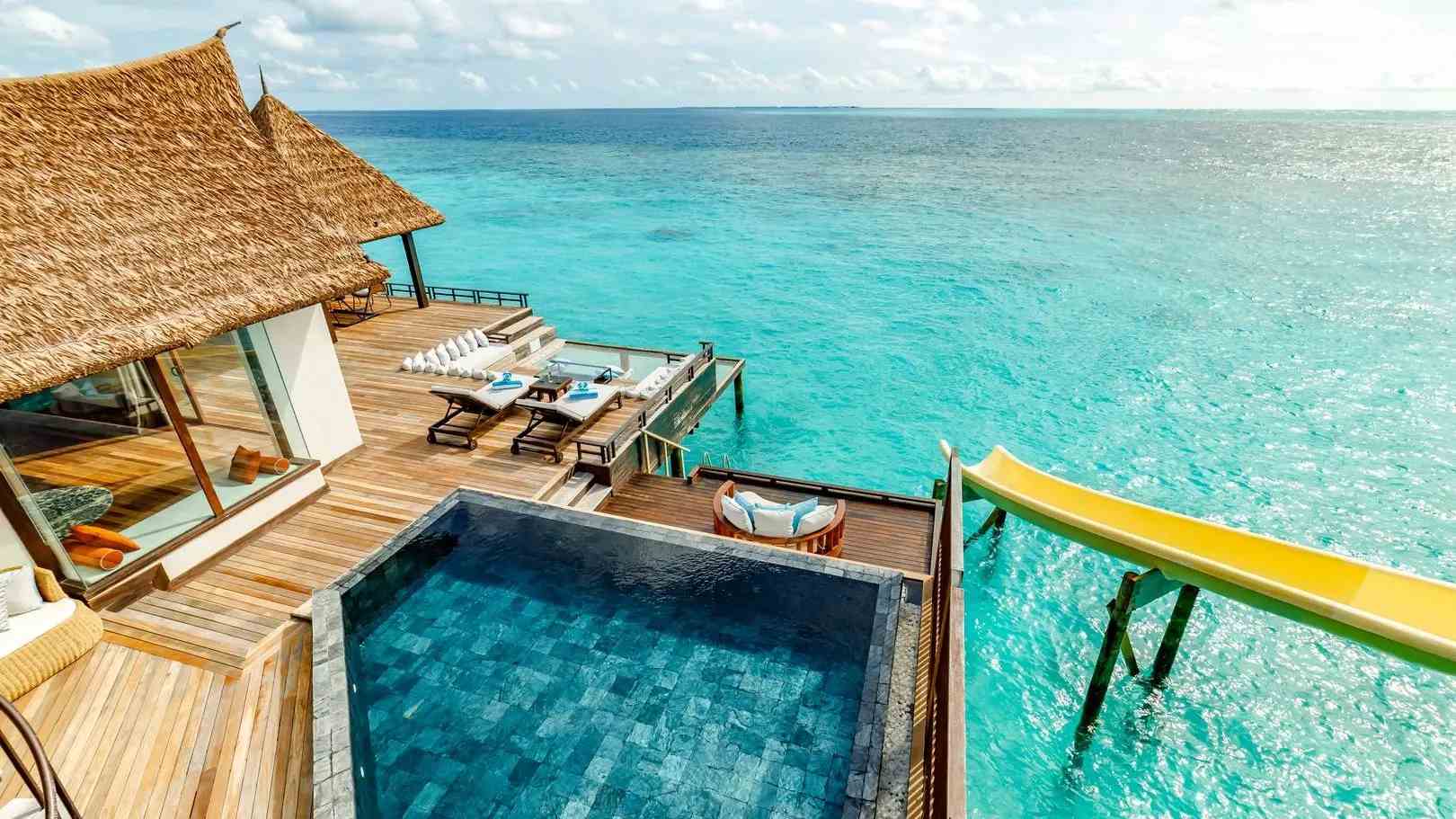 Overwater villa with a private deck and infinity plunge pool overlooking a calm turquoise lagoon at golden hour, luxury beach honeymoon setting, editorial travel photography