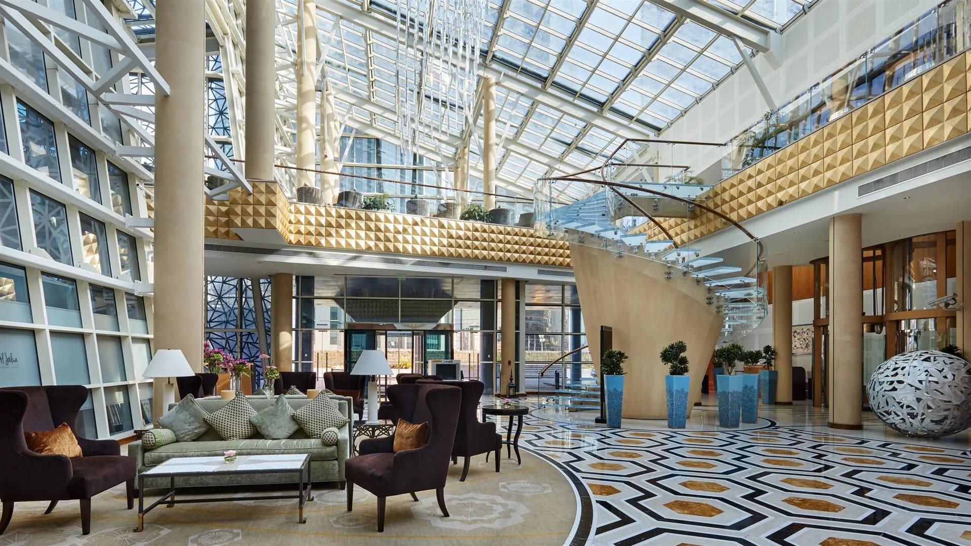 Contemporary luxury hotel lobby in Doha with minimalist Arabian design details, floor-to-ceiling windows overlooking the Gulf waterfront at dusk, editorial travel photography