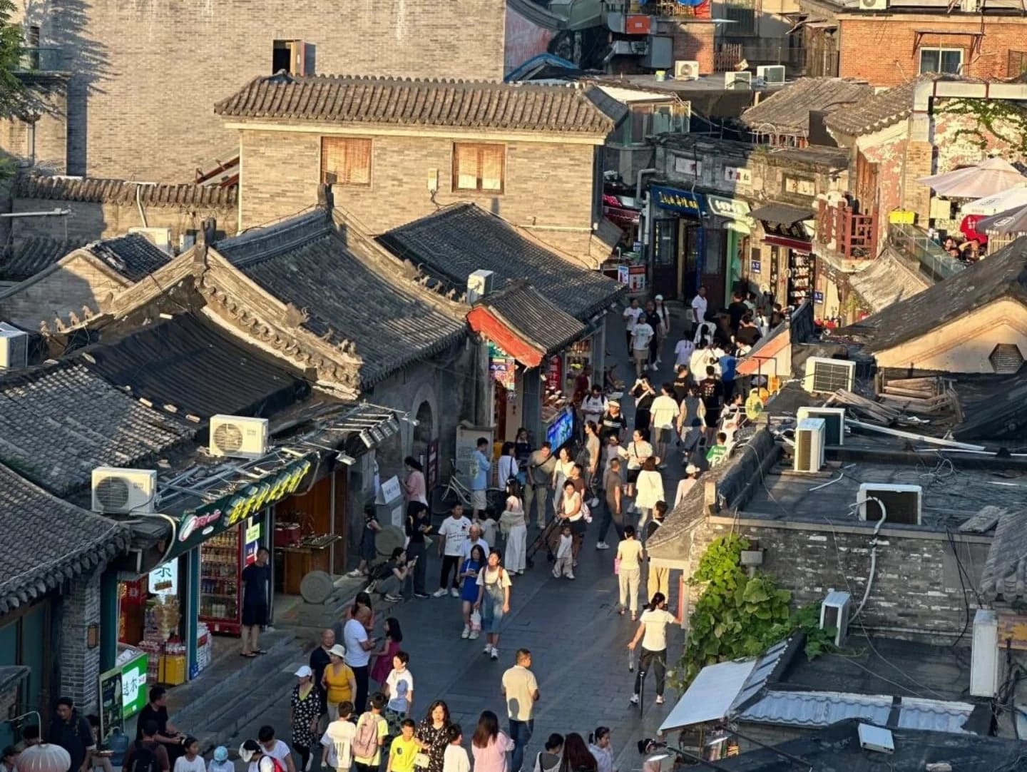 Traditional Beijing hutong alley at golden morning light with grey brick walls, red lanterns and a bicycle leaning against a courtyard gate, intimate China honeymoon, editorial photography