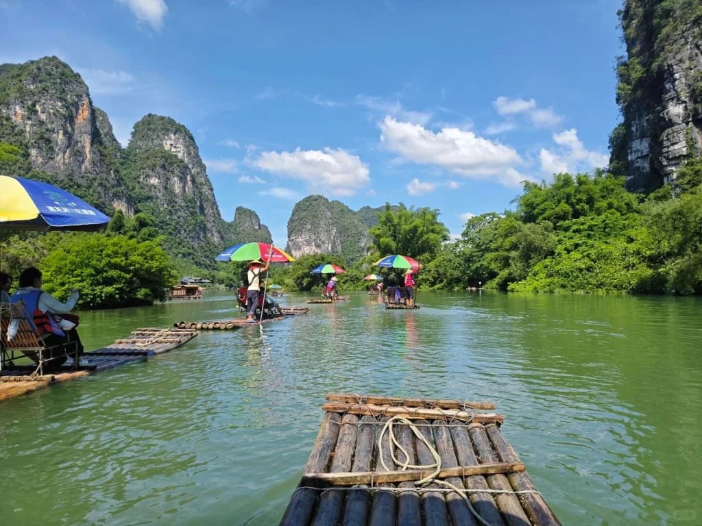 Li River in Guilin China at dawn with karst limestone peaks reflected in still water and a traditional bamboo raft gliding through morning mist, editorial travel photography