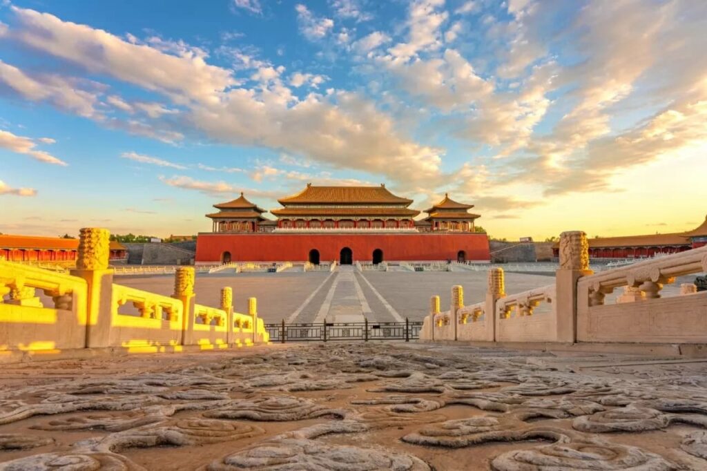 Aerial view of the Forbidden City in Beijing at golden hour with symmetrical imperial courtyards and golden tile rooftops ext