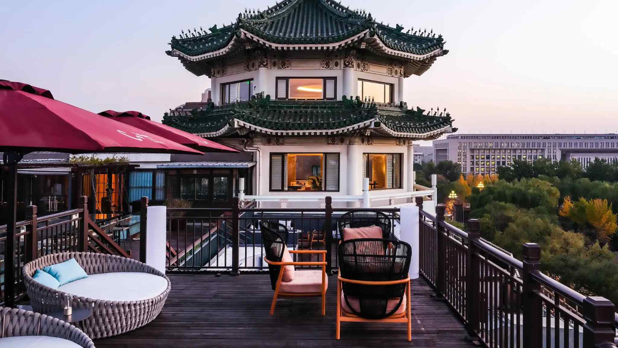 Rooftop terrace bar in Beijing at twilight with warm lighting and panoramic view of the illuminated Forbidden City and traditional rooftops, romantic evening, editorial photography