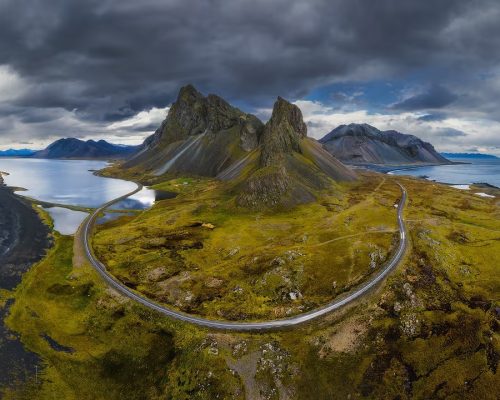 Aerial view of Iceland Ring Road winding through dramatic volcanic landscape with glaciers and green moss-covered lava fields