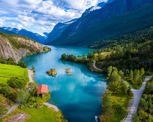 Panoramic aerial view of Geirangerfjord in Norway with deep blue water winding between steep green mountains and cascading wa