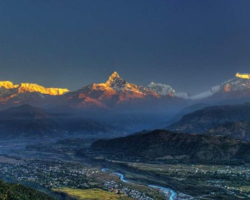 Panoramic view of Annapurna mountain range from Sarangkot viewpoint near Pokhara Nepal with golden sunrise light on snow-capp