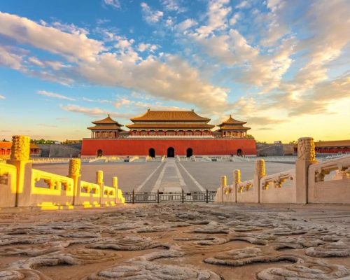 Aerial view of the Forbidden City in Beijing at golden hour with symmetrical imperial courtyards and golden tile rooftops ext